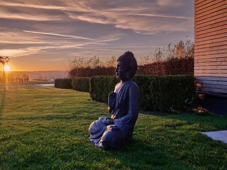 Buddafigur im Sonnenuntergang im Garten des Wellnesshotel der Birkenhof in der Oberpfalz.