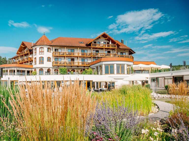 Die Aussenansicht des Hotels Der Birkenhof im Sommer umgeben von vielen Pflanzen und Streuchern.