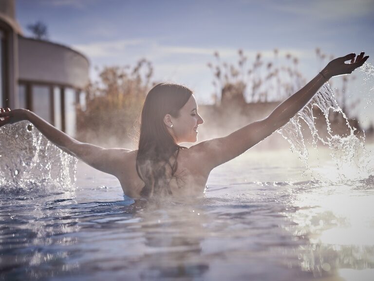 Die Frau genießt das warme Wasser des beheizten Aussenpools im Hotel Der Birkenhof.