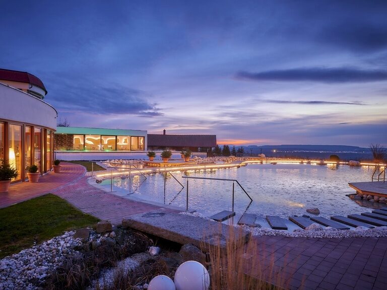 Der Natur-Badeteich des Wellnesshotel Der Birkenhof im Hotelgarten bei romantischer Abenddämmerung im Bayerischen Wald.