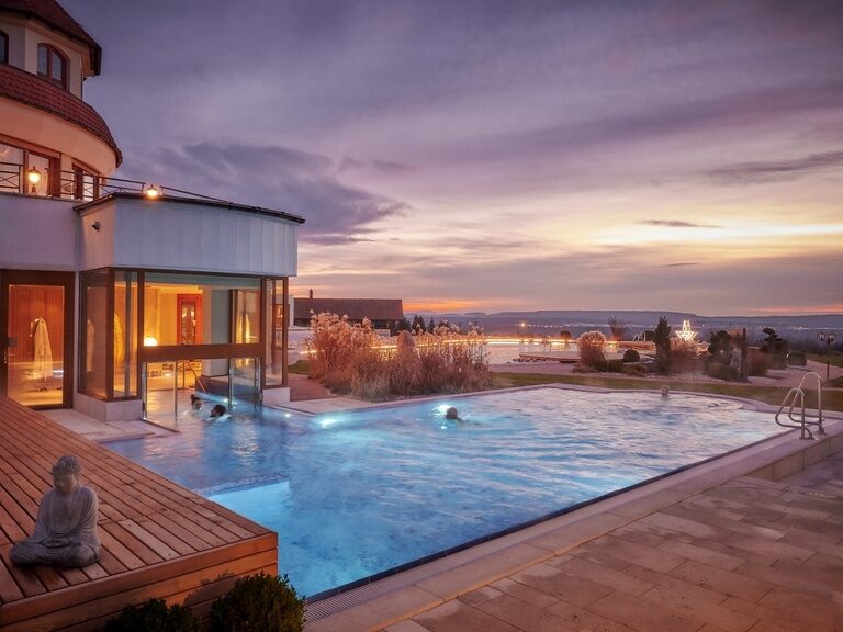 Der beheizte Außenpool bei Abenddämmerung im Aussenbereich des Wellnesshotel Der Birkenhof im Bayerischen Wald.