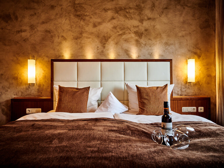 Das großzügige Bett mit stimmungsvoller Beleuchtung in der Turm Suite des Hotel Der Birkenhof.