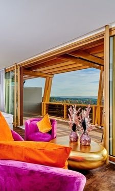 Der helle Wohn- und Schlafbereich der Sky Suite mit großflächiger Fensterfront und traumhaften Ausblick über den Balkon.