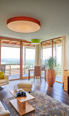 Die große und helle Eck Suite mit Blick durch die Fensterfront auf den Balkon im Wellnesshotel Der Birkenhof in Bayern.