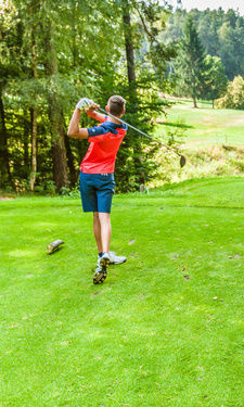 Zwei Frauen beobachten einen Golfer beim Abschlag auf einem Golfplatz in Bayern.