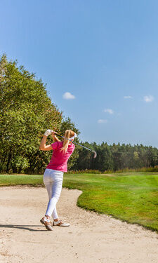 Die Frau spielt Golf in der Sandgrube auf einem großen Golfplatz in Bayern.