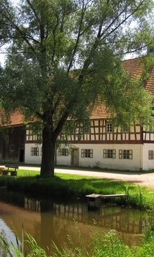 Das historische Volkskundemuseum in Burglengenfeld neben einem Bach im Sommer.