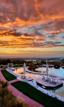Der wunderschöne Ausblick über den Garten und den Aussenpoolbereich bei Sonnenuntergang im Wellnesshotel Der Birkenhof in Bayern.