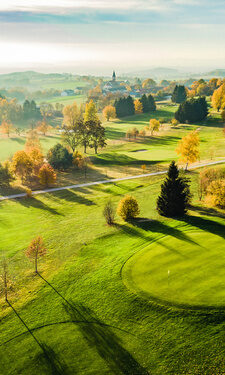 Ein Vogelperspektiveblick auf einen malerischen Golfplatz umgeben von Bäumen.