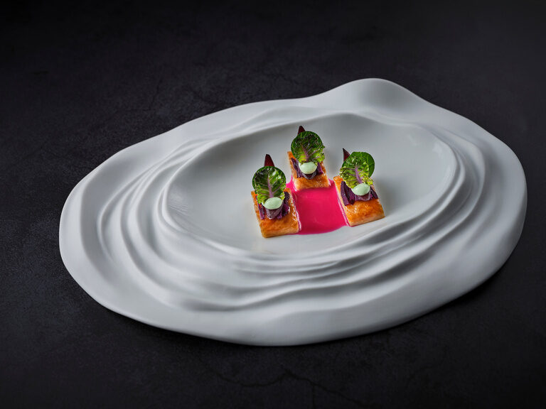 Ein kunstvoll angerichtetes Gericht auf einem weißen Porzellanteller im Restaurant Eisvogel.