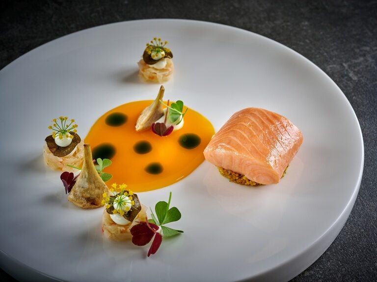 Das Fischgericht mit Lachs auf einem feingarnierten Teller.