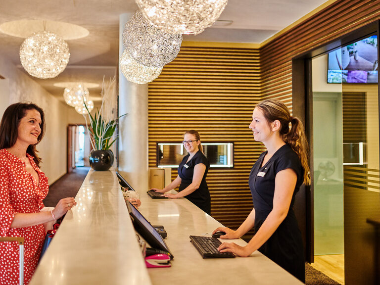 Die Frau checkt an der Rezeption des Wellnesshotel Der Birkenhof in der Oberpfalz ein.
