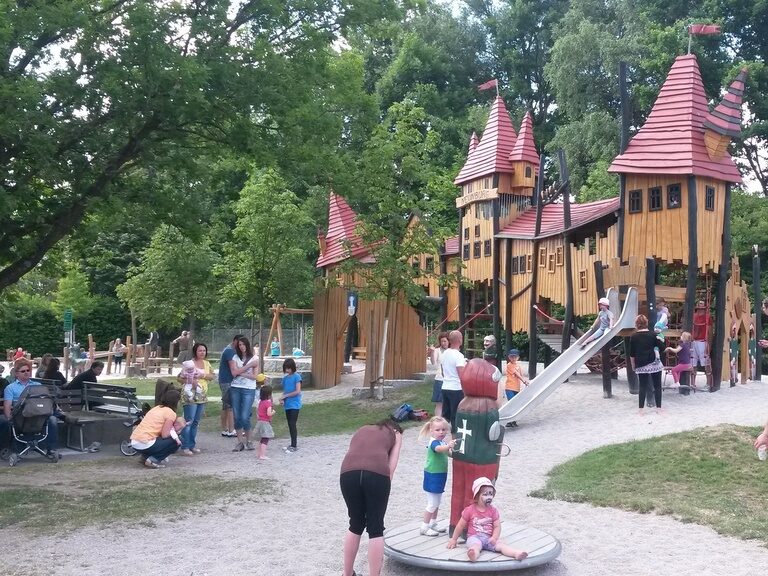 Eine Gruppe von Menschen spielt fröhlich im Park bei einem Erlebnissspelplatz, idealer Ort für Erholung und Freizeit mit Kindern.