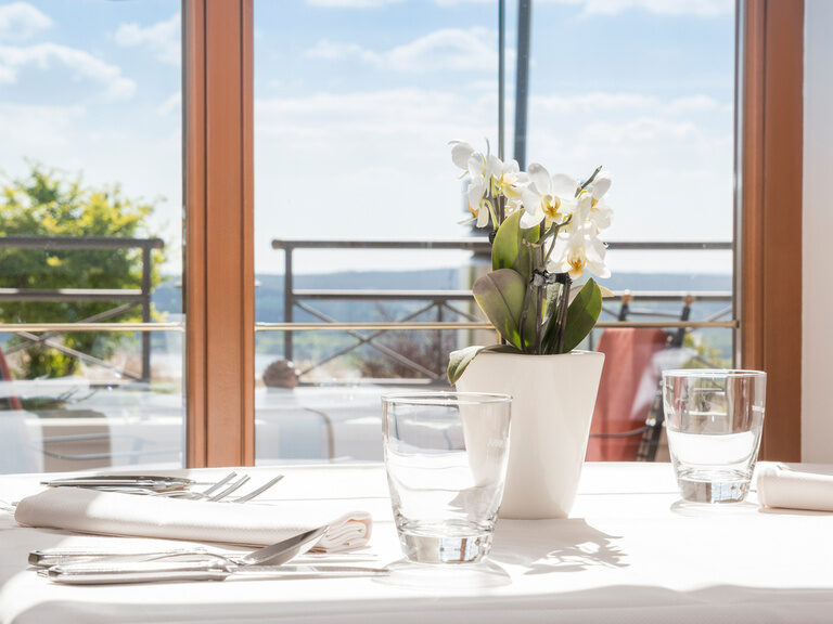Der elegant eingedeckte Tisch ist ein romantischer Fensterplatz im Restaurant Turmstube des Wellnesshotel Der Birkenhof.