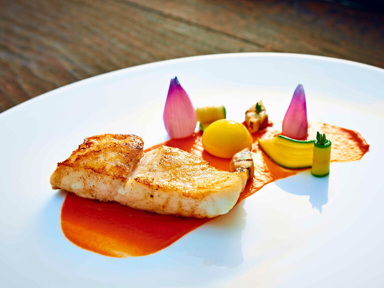 Das farbenfohe Steinbuttgericht elegant mit filigranen Gemüseschnitzereien aus dem Restaurant Eisvogel.