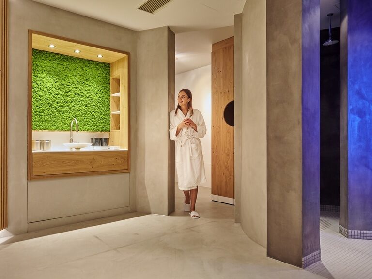 Die Frau lehnt an der Erfrischungsecke nach dem Saunagang und genießt zur Erfrischung ein Getränk.