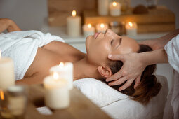 Eine Frau liegt entspannt auf einer Liege des Betula Spa mit Kerzen im Hintergrund.