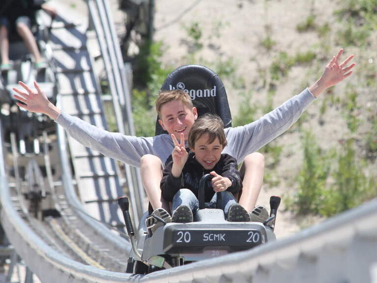 Die aufregende Sommerrodelbahnfahrt bringt zwei Jugendlichen Spaß und Abenteuer im Freizeitpark Monte Kaolino.