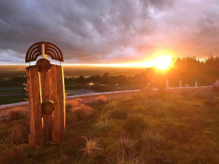 Gartendeko aus verschiedenen Materialien im Hotelgarten mit Panoramablick auf den Sonnenuntergang.