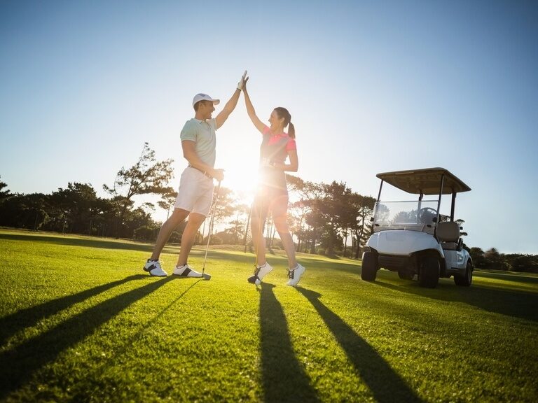 Das Golferpaar gibt sich ein High-Five auf einem Golfplatz in der Nähe des Hotel Der Birkenhof in Bayern