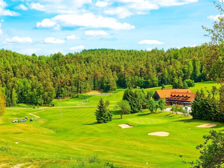 Ein gepflegter Golfplatz in einem Golfclub in der Oberpfalz, umgeben von majestätischen Bäumen.