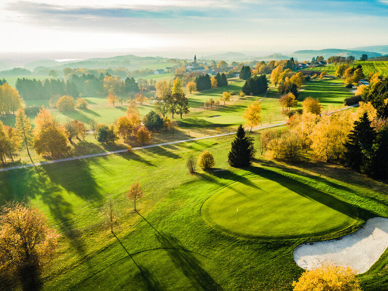 Ein Vogelperspektiveblick auf einen malerischen Golfplatz umgeben von Bäumen.