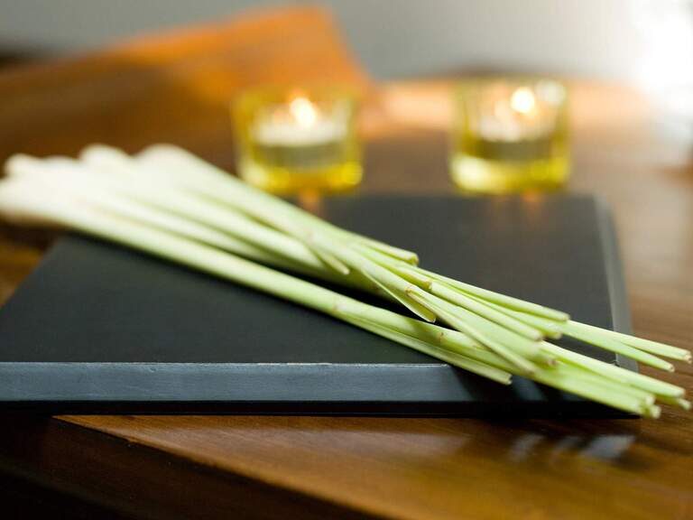 Ein Bündel mit grünen Naturspaprodukten liegt auf einem Brett aus Holz vor kleinen Ölgefäßen im Wellnesshotel der Birkenhof.