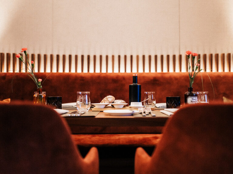 Ein Tisch mit zwei Stühlen und einer Blumenvase im Kaminrestaurant  des Hotels der Birkenhof in Bayern.