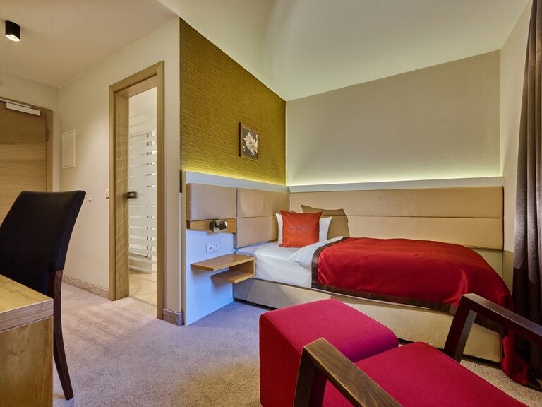 Ein geschmackvoll gestaltetes Komfort Einzelzimmer im Hotel Birkenhof Therme mit einem Bett und einem Schreibtisch.