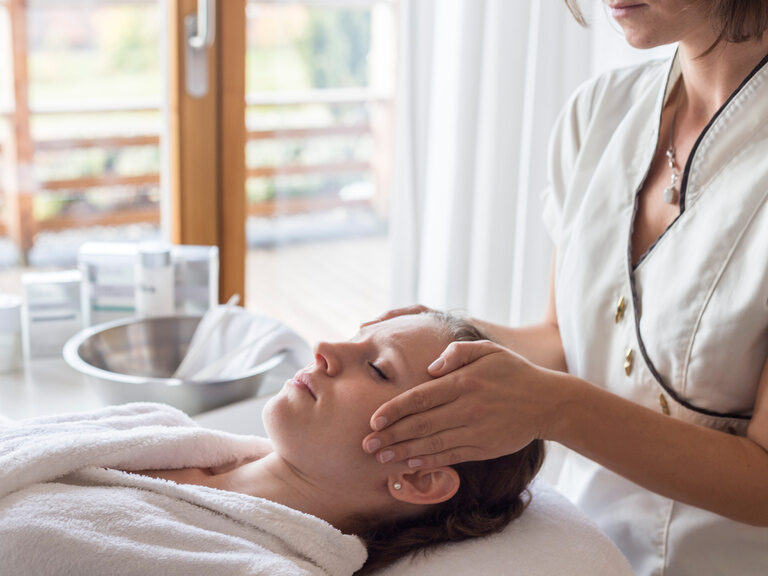 Die wohltuende Kopfmassage im Wellnessbereich wird von professionellen Personal an den Gästen ausgeübt.