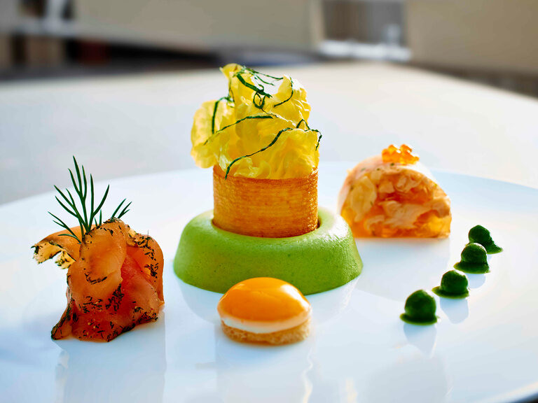 Lachsrose mit filigran gearbeiteter Garnierung auf einem weissen Teller aus dem Restaurant des Wellnesshotel Der Birkenhof.