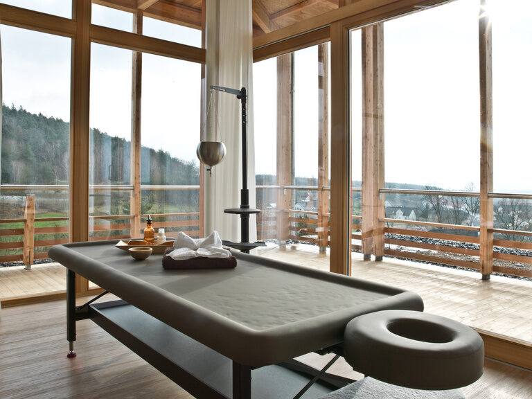 Der Anwendungsraum mit vorbereiteter Massage-Liege und schöner Aussicht im Wellnesshotel Der Birkenhof in Bayern.
