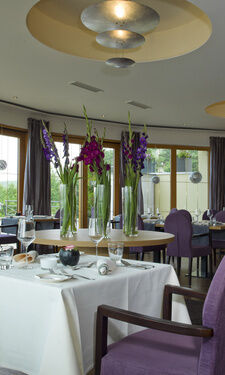 Restaurant Landart mit gedeckten Tischen, lila Stühlen und Blumendekoration