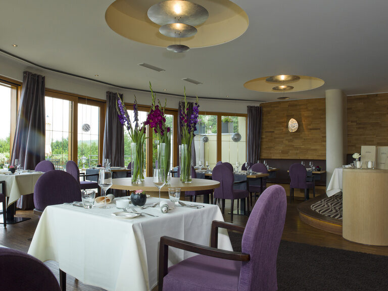 Das Restaurant Landart mit gedeckten Tischen, lila Stühlen und Blumendekoration in der Oberpfalz.