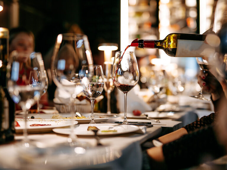 Ein gedeckter Tisch im Restaurant bei dem Wein serviert wird.
