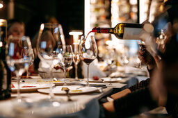 Ein gedeckter Tisch im Restaurant bei dem Wein serviert wird.