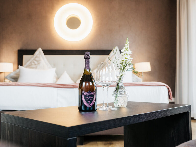 Eine Sektflasche auf einem Tisch im De Luxe Doppelzimmer Seeblick des Hotels der Birkenhof beim Bayerischen Wald.