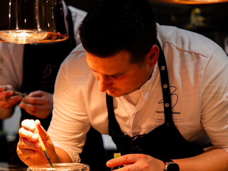 Der Sternekoch Sebastian Obendorfer des Restautrants Eisvogel graniert unter Wärmelanten einen Teller.