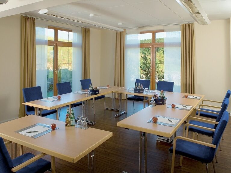 Der vorbereitete Tagungsraum mit blauen Stühlen und U-Form Bestuhlung im Tagungshotel Der Birkenhof in der Oberpfalz.