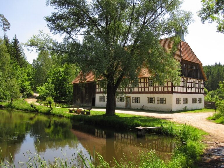 Das historische Volkskundemuseum in Burglengenfeld neben einem Bach im Sommer.