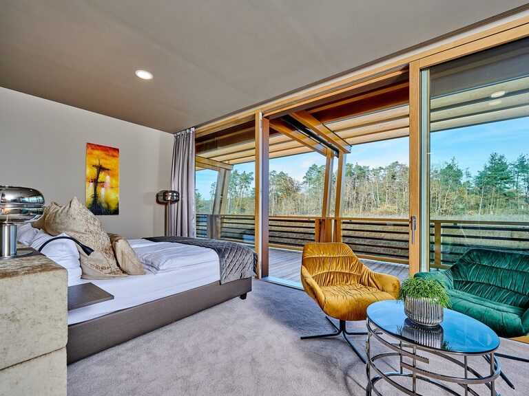 Moderne Wald Suite im Hotel Der Birkenhof mit großer Fensterfront und Zugang auf den Balkon.