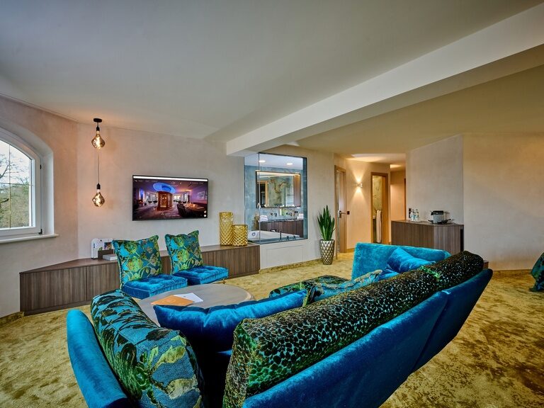 stilvoller Wohnbereich mit Couch und Flachbildfernseher in der Panorama Suite Modern - Der Birkenhof Spa & Genuss Resort in der Oberpfalz.